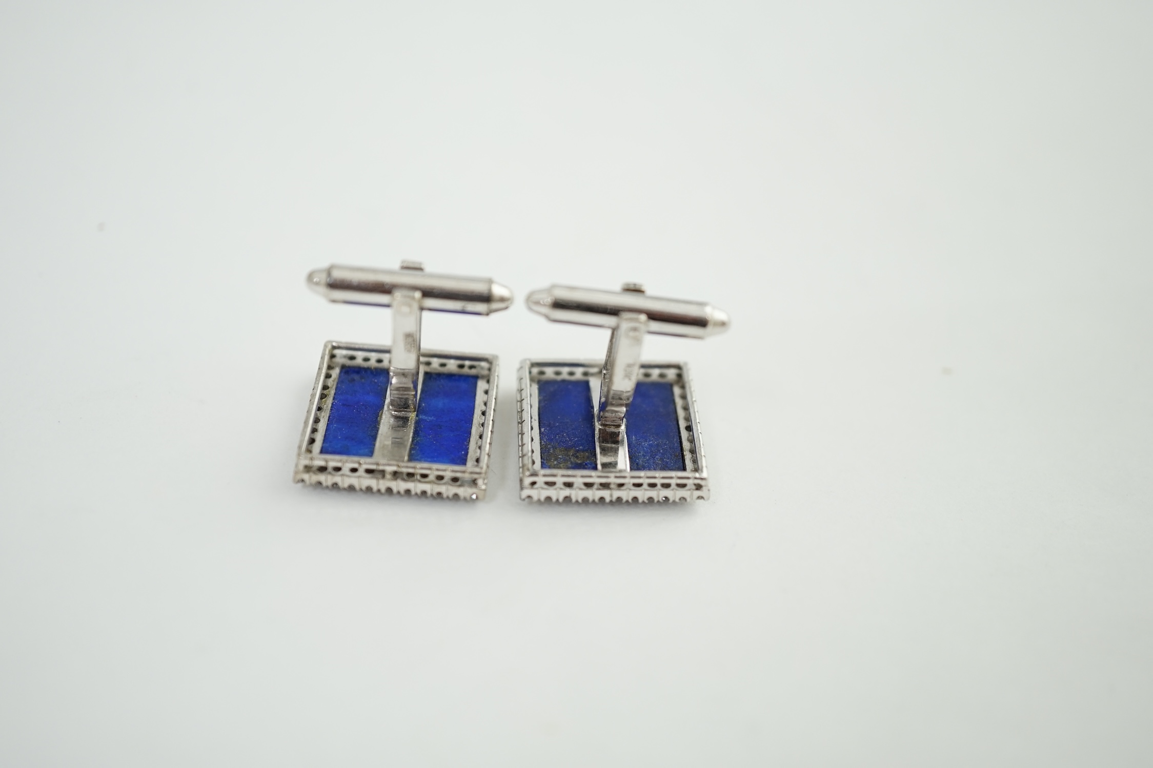 A pair of 18K white metal, lapis lazuli and diamond set tablet cufflinks, each lapis stone surrounded by forty claw set diamonds, 17mm, gross weight 14.1 grams. Condition - fair